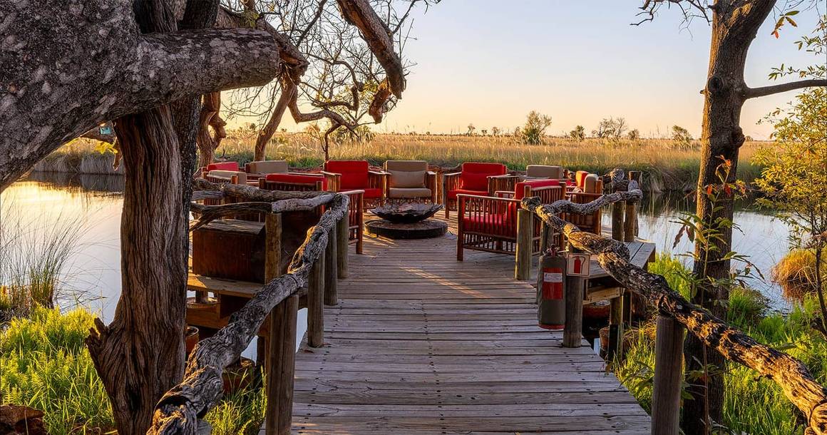 Camp Xakanaxa boma deck with fire pit at sunset on the lagoon