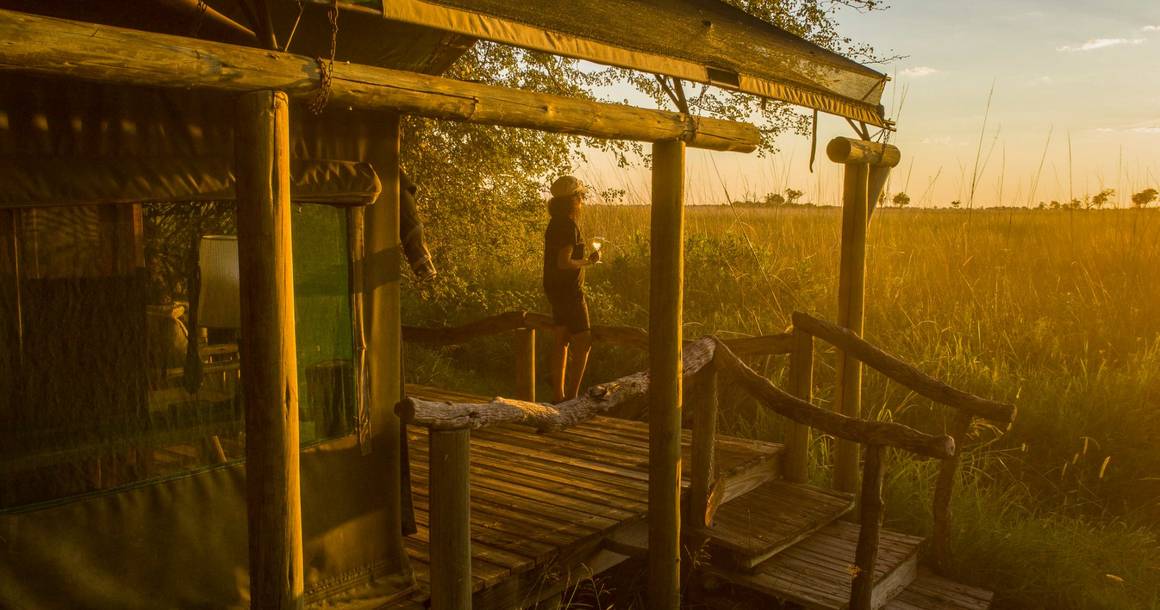 Camp Xakanaxa guest on private deck overlooking the lagoon at golden hour