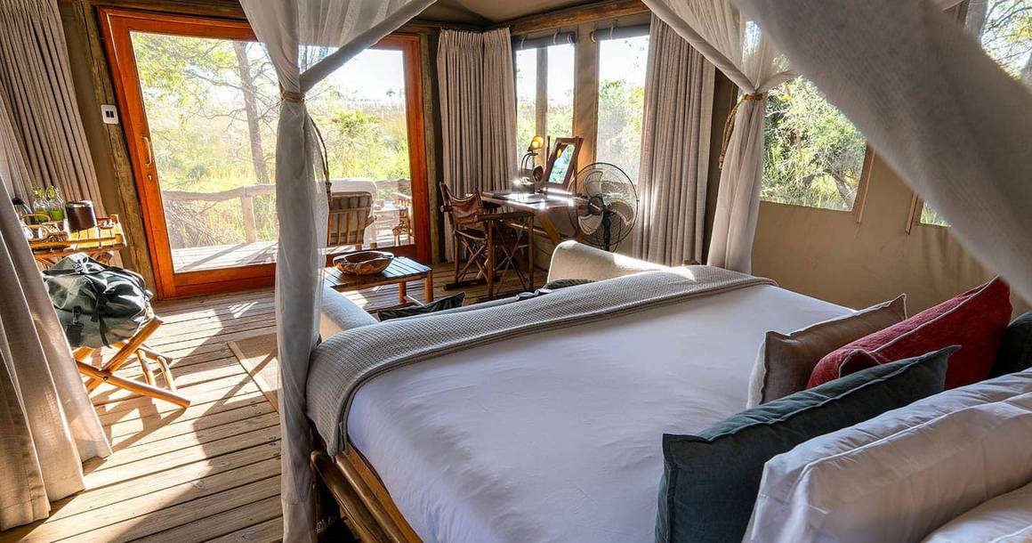 Camp Xakanaxa tented suite with canopy bed and bush view