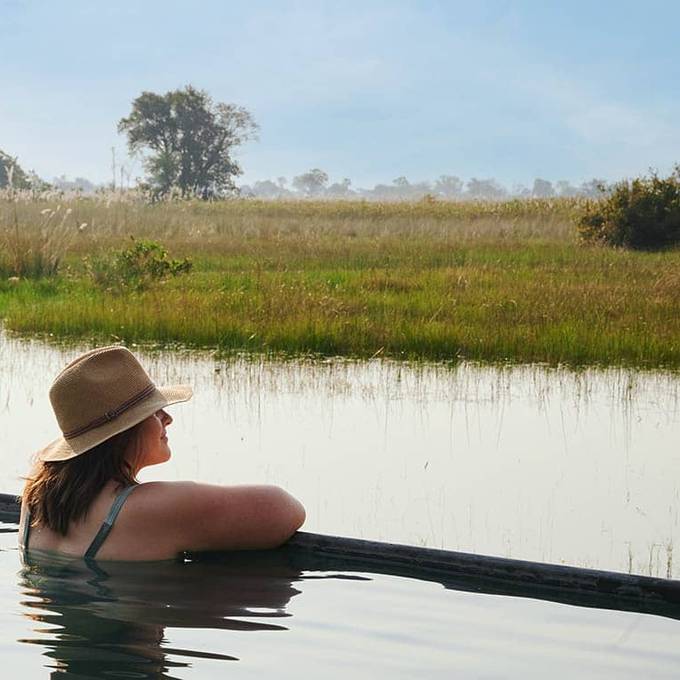 Guest relaxing in Camp Okavango infinity pool overlooking the Delta