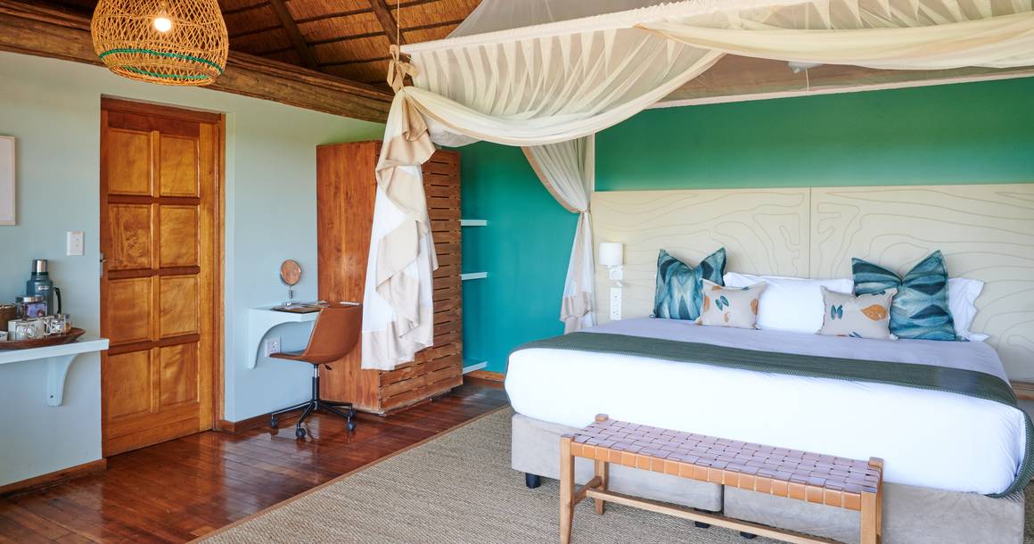 Leroo La Tau bedroom with teal accent wall and canopy bed