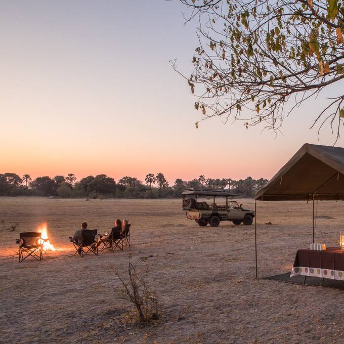 Letaka camp at sunset with palm-lined horizon and Land Cruiser