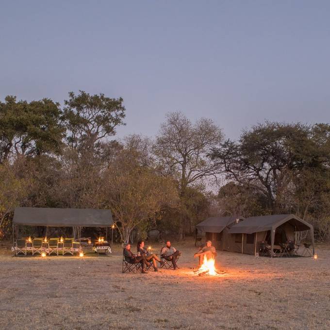 Letaka mobile tented camp at dusk with campfire and lanterns