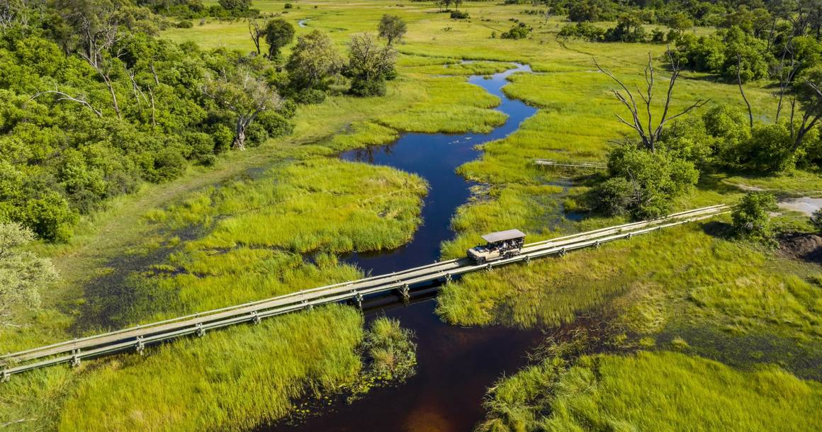 Safari vehicle crossing a bridge over the Khwai floodplain