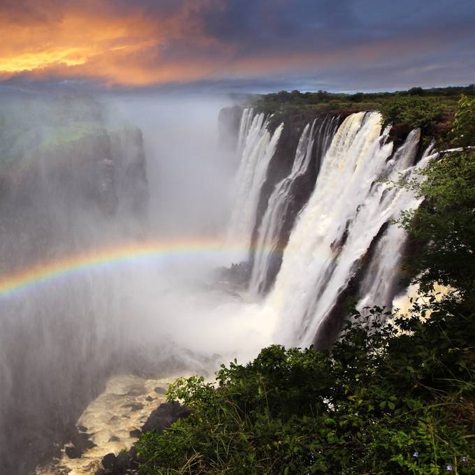 Victoria Falls cascade with rainbow at sunset from the Zimbabwe side